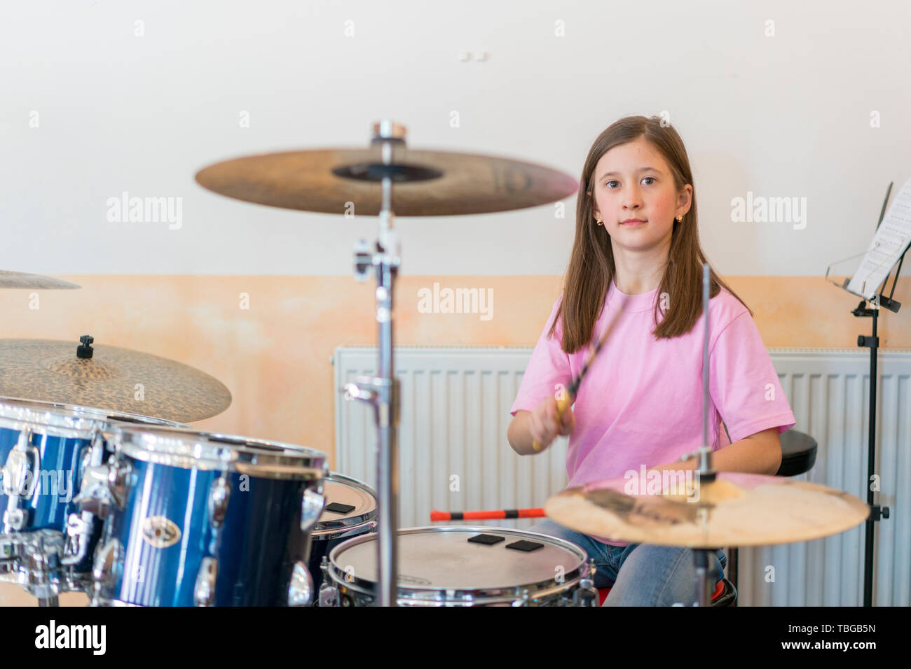 Little caucasian girl drummer playing the elettronic drum kit and ...