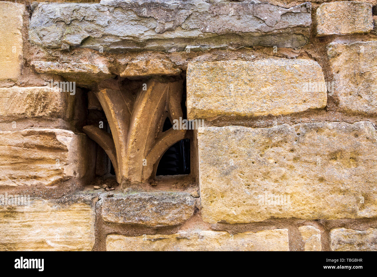 Church stone ornament fragments embedded in a Cotswold stone wall Stock Photo