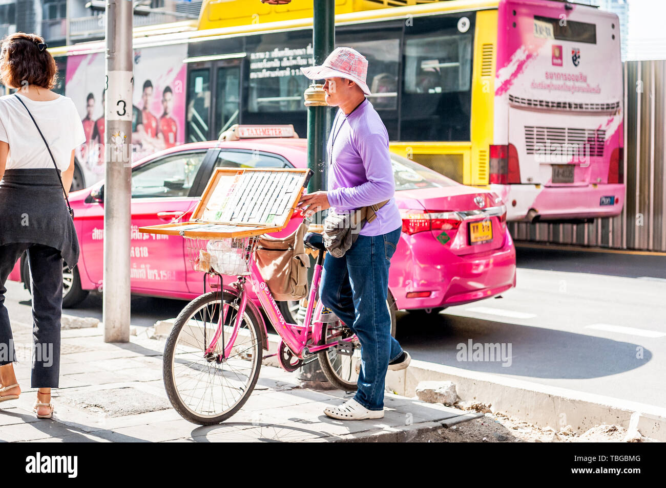 A lottery ticket seller travels through Bangkok on his bicycle selling tickets on Sukhumvit Rd. Thailand. Stock Photo