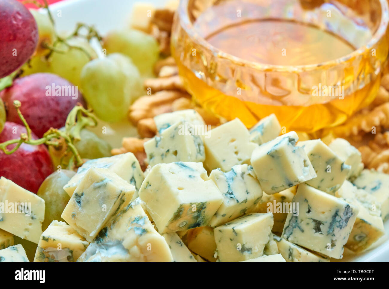 Different kinds of cheese, grapes, walnuts and honey gourment assorted close-up Stock Photo