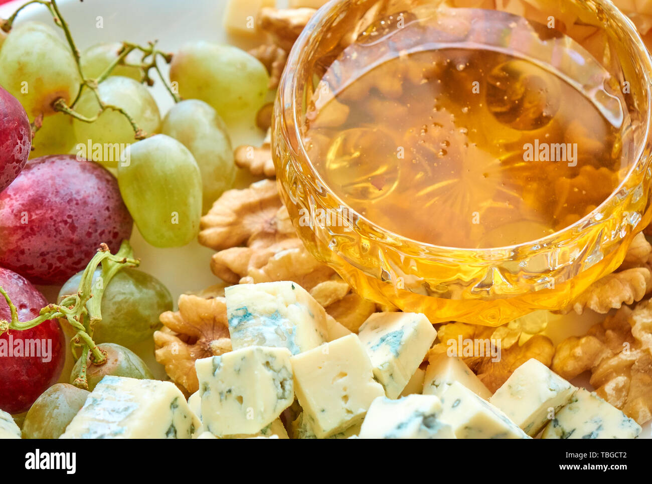 Different kinds of cheese, grapes, walnuts and honey gourment assorted close-up Stock Photo
