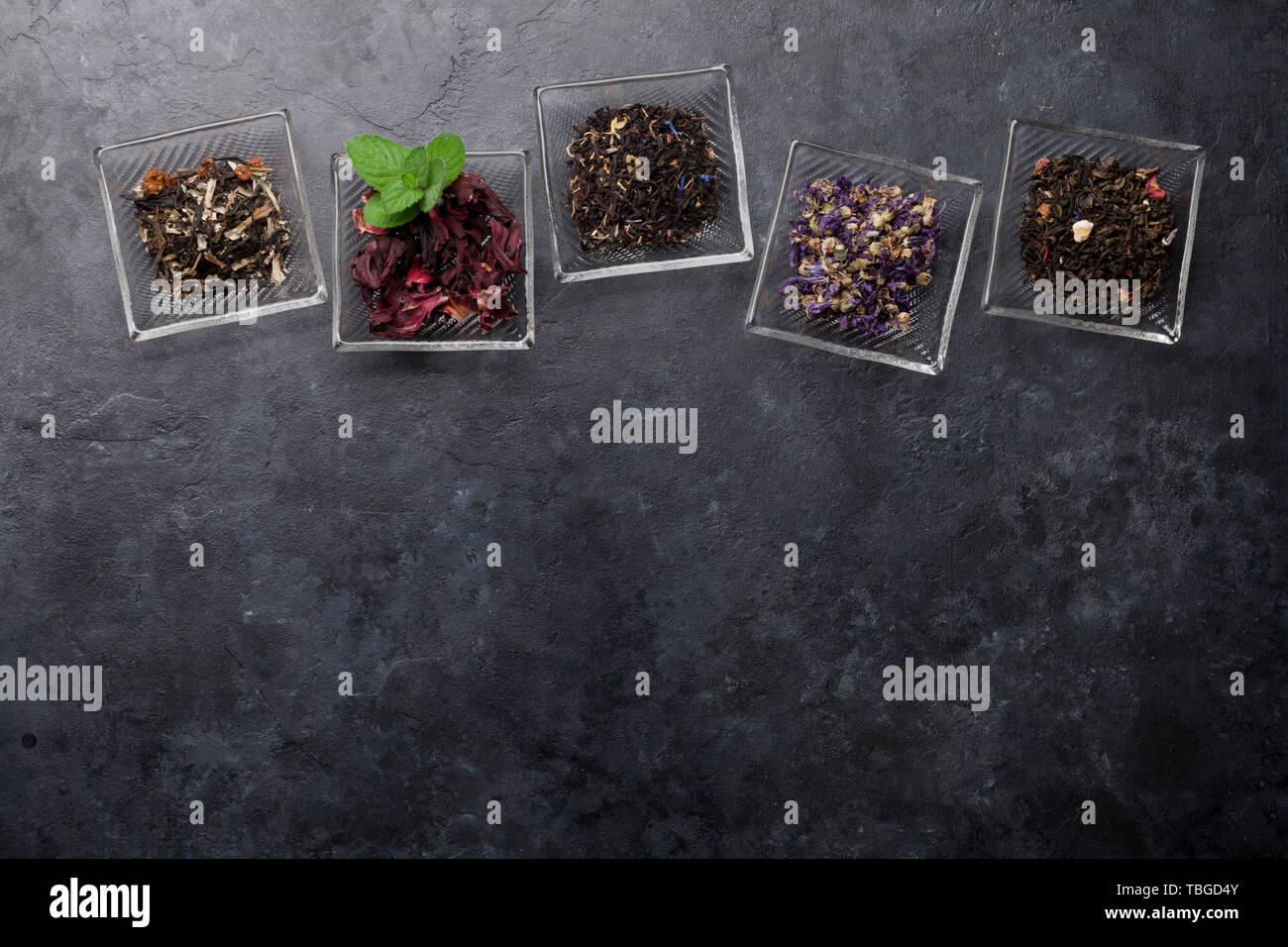 Dry Tea Set of different herbal and fruit dry teas in bowls on stone table. Top ...