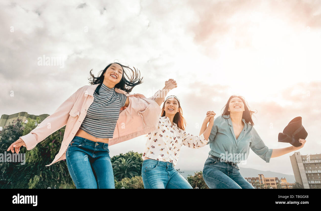 Happy Asian girls jumping outdoor - Young women friends having fun during university break Stock Photo
