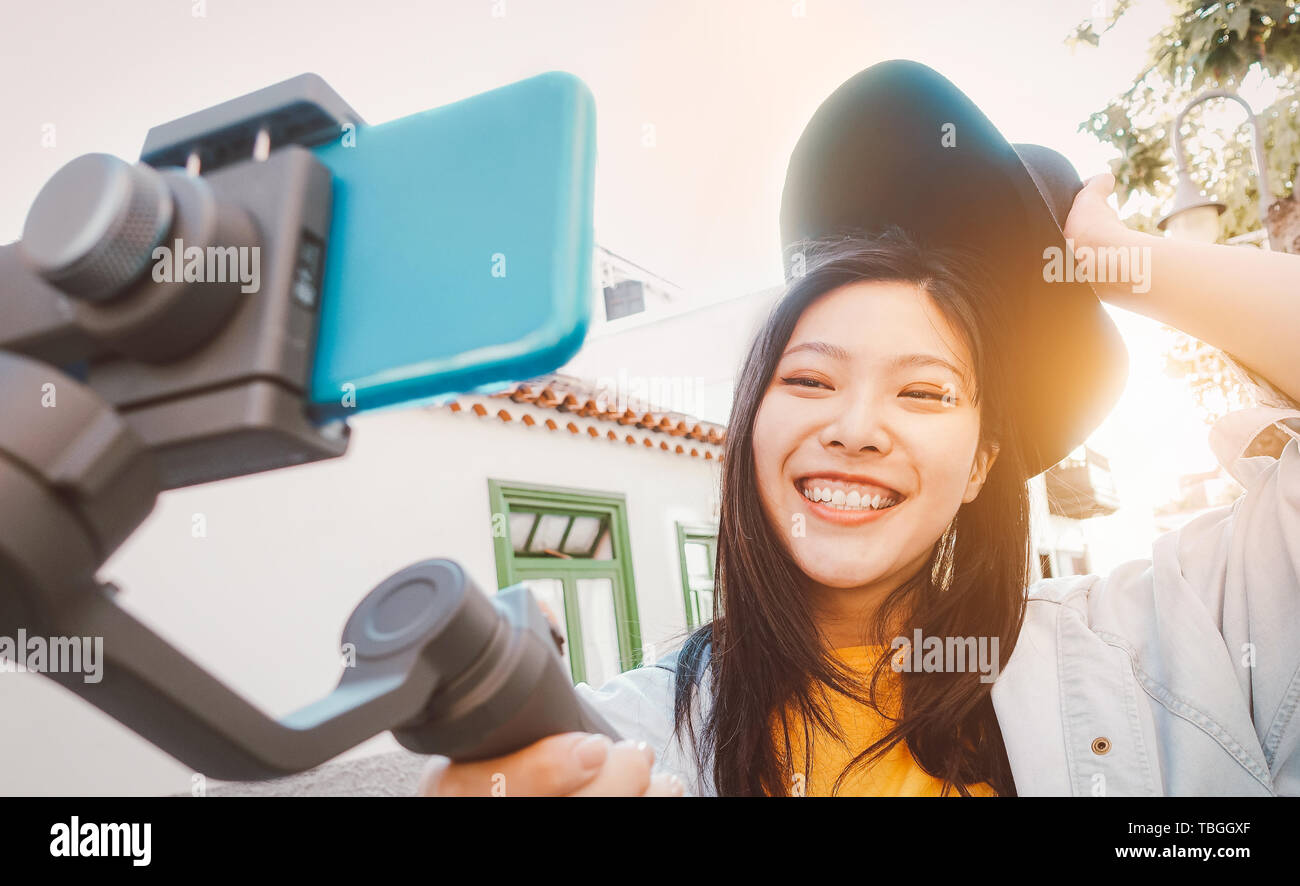 Asian woman making video with smartphone gimbal outdoor - Happy Asiatic girl having fun with new technology trends for social media Stock Photo