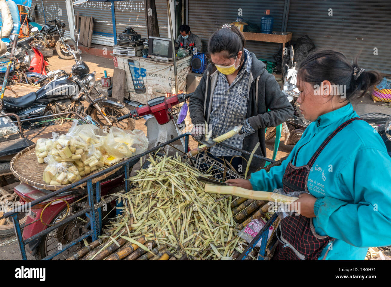 Laotian women carving sugar cane near Daoheuang Market in Pakse, Laos Stock Photo