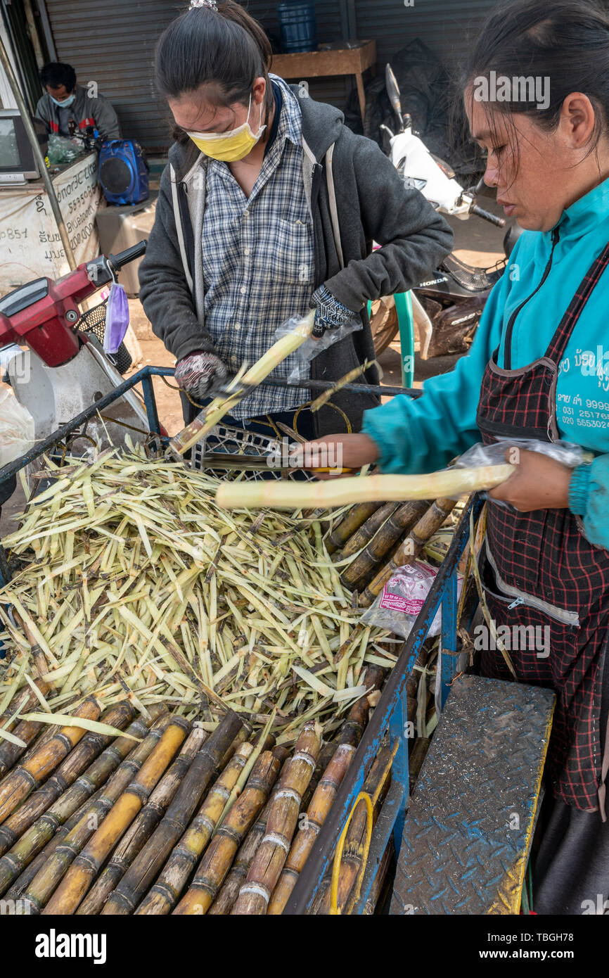 Laotian women carving sugar cane near Daoheuang Market in Pakse, Laos Stock Photo