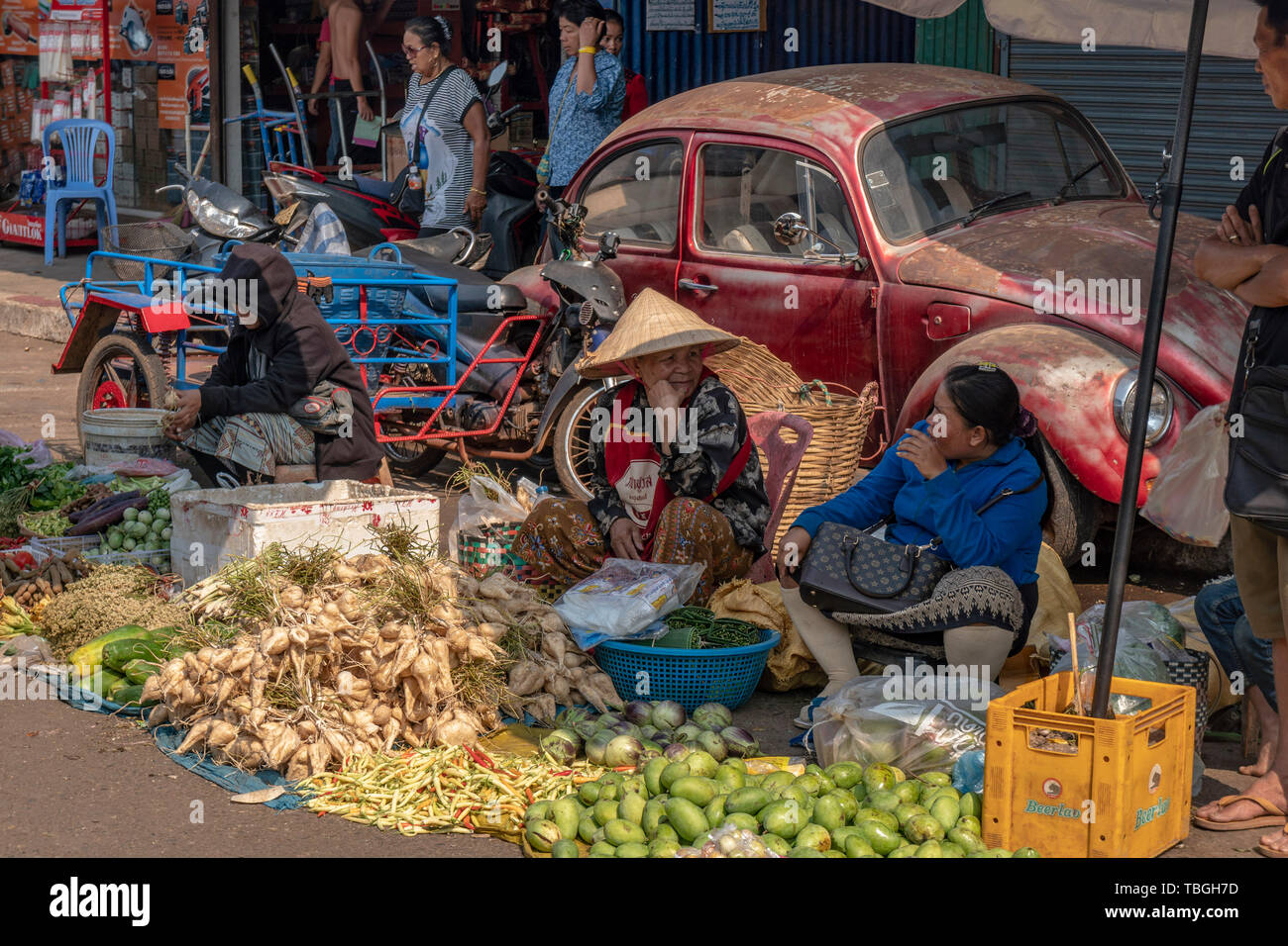 Old women selling fruits and vegetables near Daoheuang Market in Pakse, Laos backgroung VW Beetle, Oldtimer Stock Photo