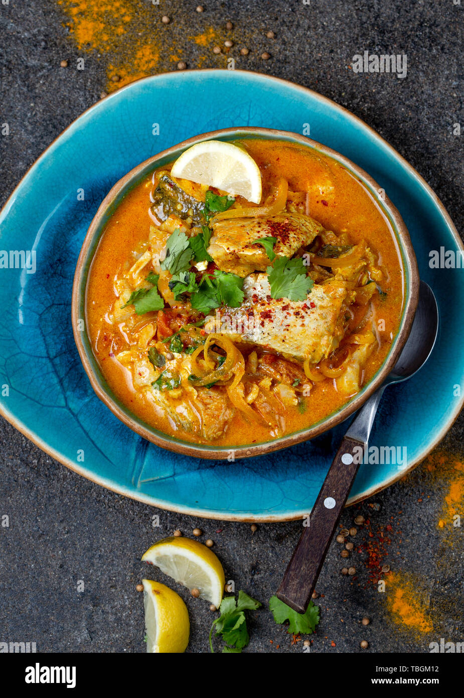 INDIAN FOOD. Traditional KERALA FISH CURRY with naan bread, gray plate, black background. Stock Photo