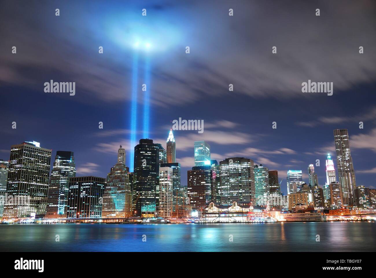 Remember September 11. New York City Manhattan panorama view at night with office building skyscrapers skyline illuminated over Hudson River and two light beam in memory of September 11. Stock Photo