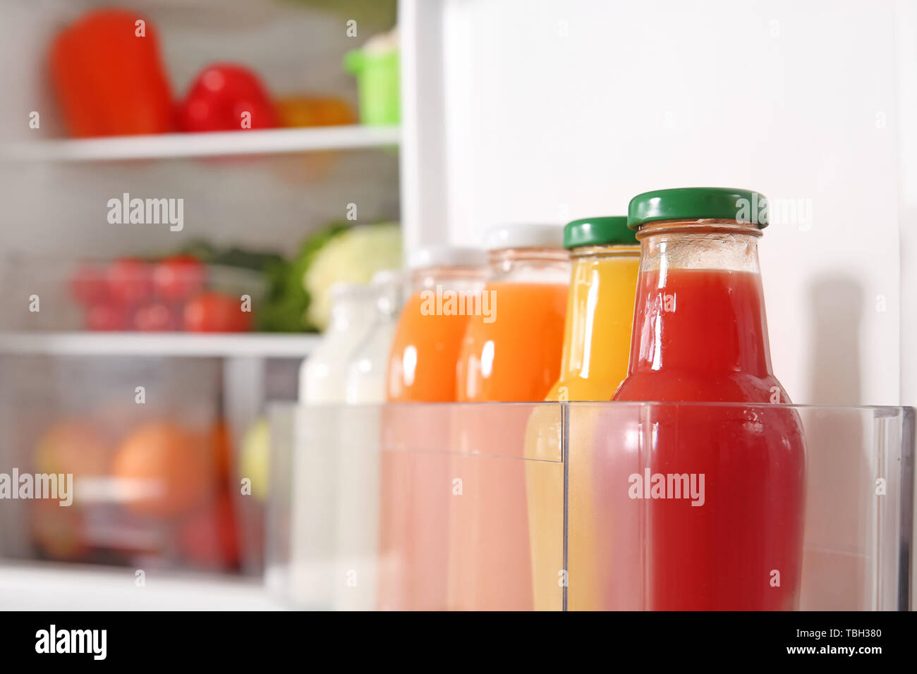 https://c8.alamy.com/comp/TBH380/bottles-with-milk-and-juice-in-open-fridge-TBH380.jpg