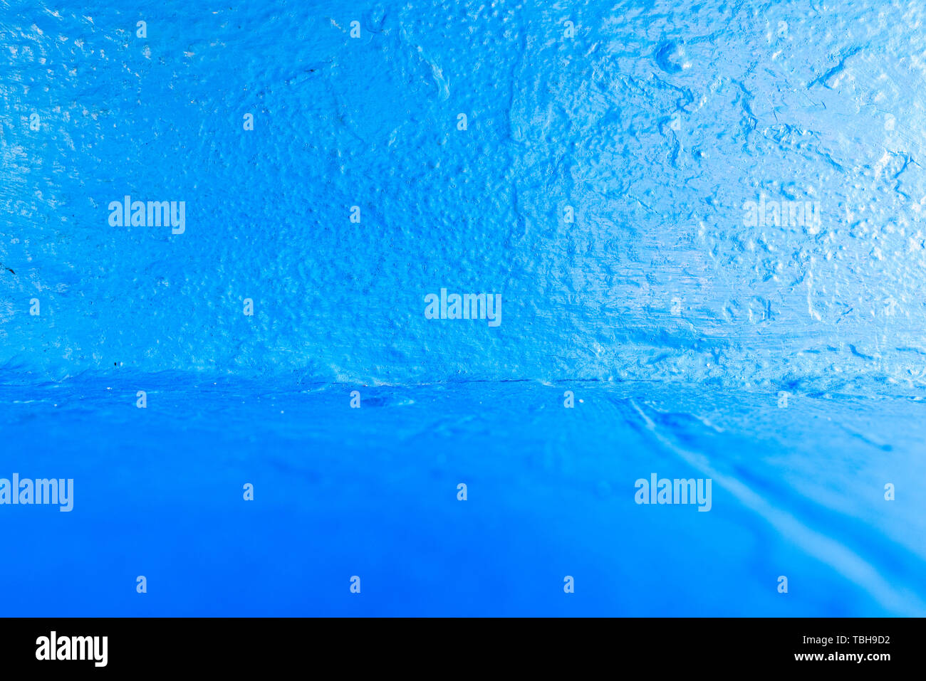 Background with rough texture of a wall painted blue and illuminated at ...