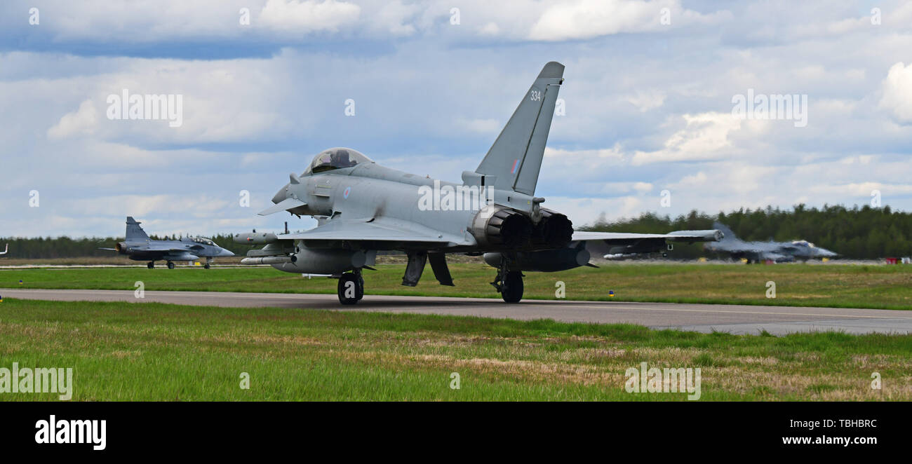 A Royal Air Force Typhoon FGR4 taxis behind Swedish Air Force JAS 39 Gripens prior to flight operations in support of Arctic Challenge Exercise 2019 at Kallax Air Base, Luleå, Sweden, May 30, 2019. ACE 19 is a Nordic aviation exercise that provides realistic, scenario-based training to prepare forces for enemy defensive systems. U.S. forces are engaged, postured and ready to deter and defend in an increasingly complex security environment. (U.S. Navy Photo by Chief Mass Communication Specialist John M. Hageman) Stock Photo