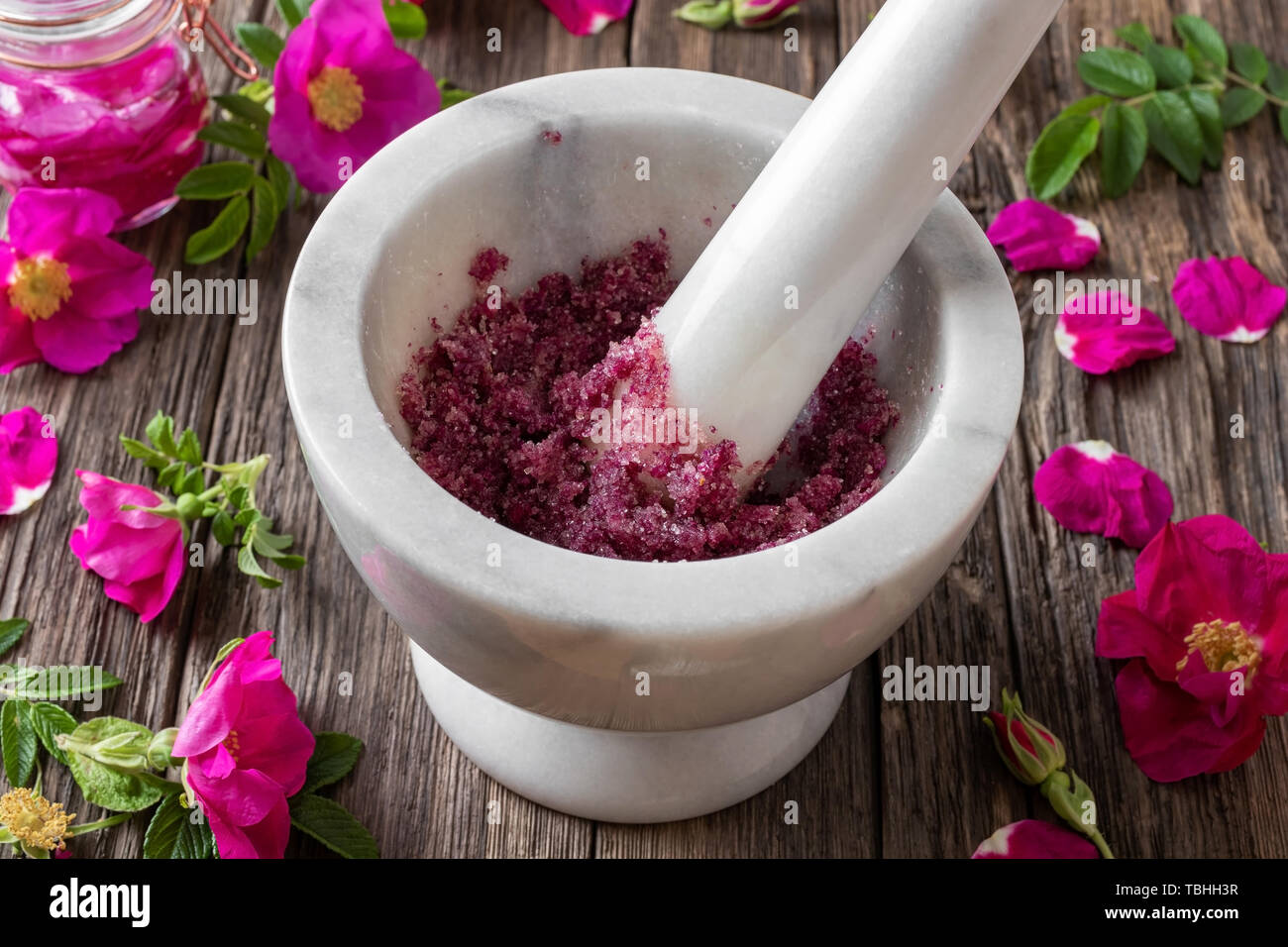 Fresh Rugosa rose flowers crushed with cane sugar in a marble mortar