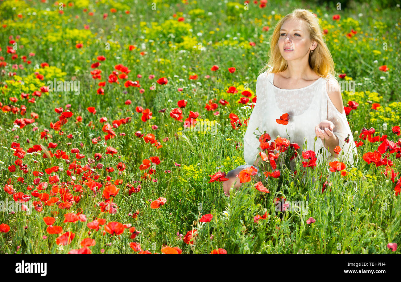 Beautiful woman wearing white dress in poppy field and enjoying summer ...