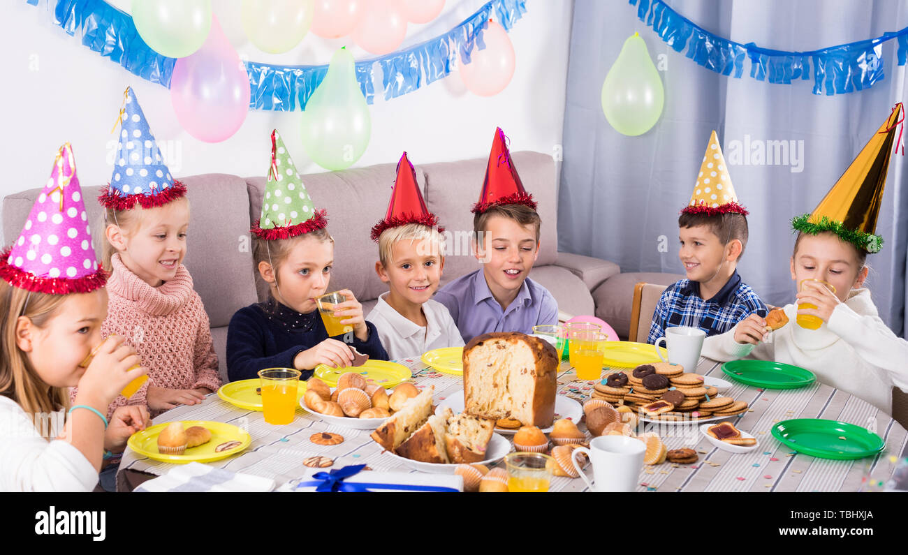 Joyous children having dinner to celebrate friend’s birthday Stock