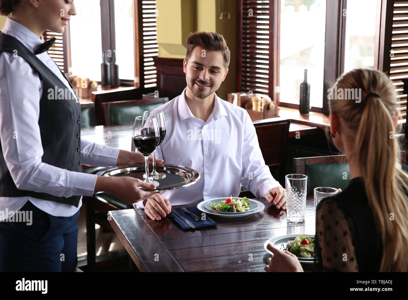 Waiter serving guests in restaurant Stock Photo