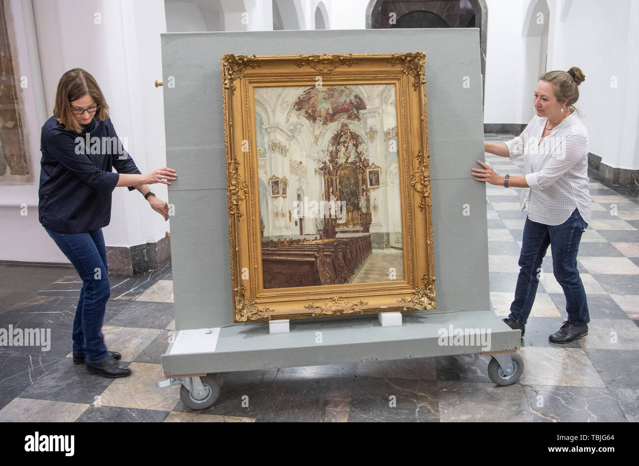 Wiesbaden, Germany. 21st May, 2019. Two employees of the Landesmuseum push the painting "Kirche zu Rott am Inn" by Fritz Beckert on a trolley through the entrance area. Some of the works of art that the National Socialists had stolen from their owners are still stored in the collections of Hessian museums today. (Zu dpa "Provenance Research: Science meets Art" of 02.06.2019) Credit: Boris Roessler/dpa/Alamy Live News Stock Photo