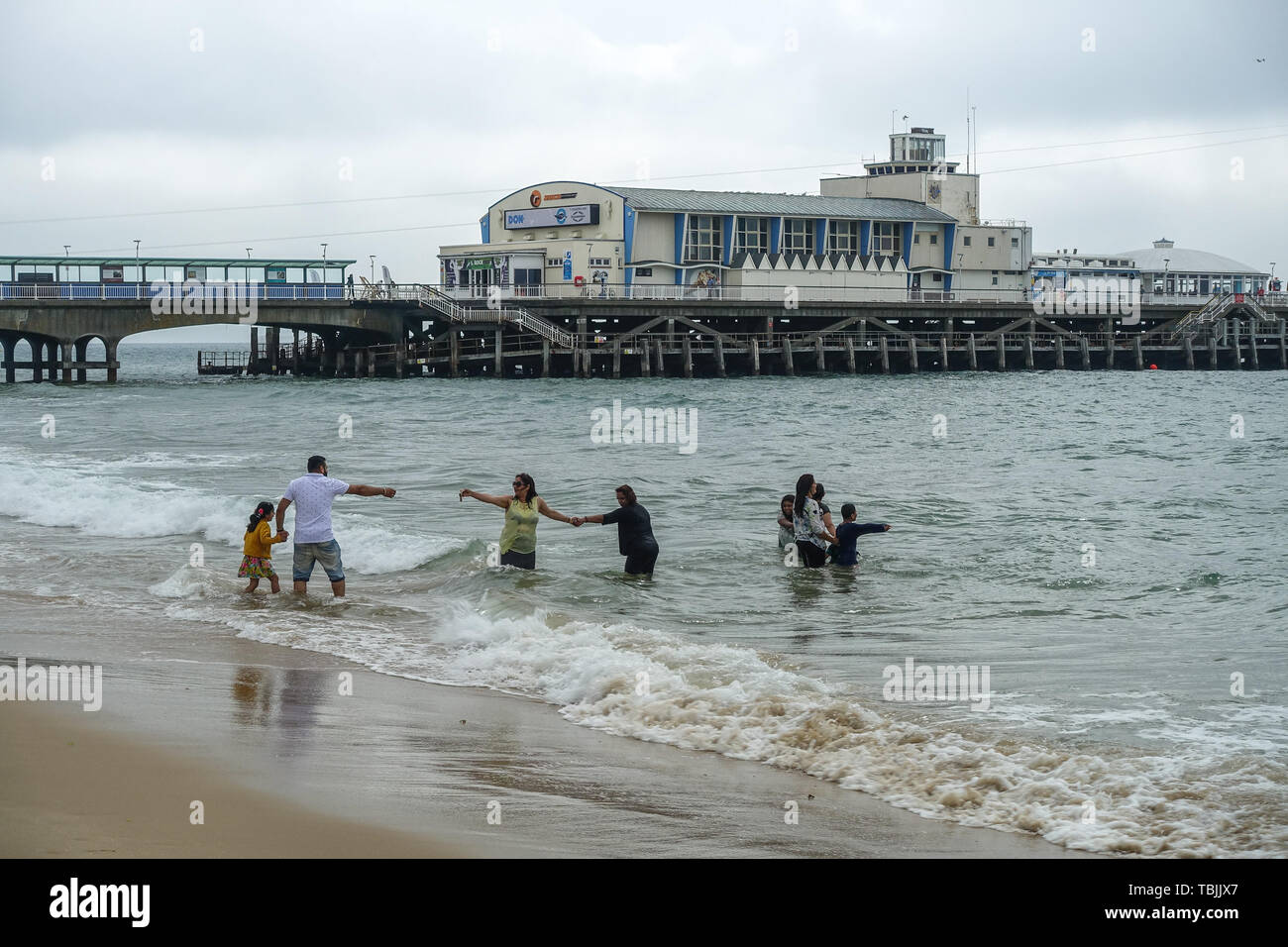 Bournemouth, Dorset, UK, 2nd June 2019. A cool start in the south of England meant that some visitors to the beach were well wrapped up in coats and hoodies. This family took to the sea fully clothed. The forecast was for 29 degrees Celsius but has only reached 20 degrees mid morning with a cool wind. Credit: Mick Flynn/Alamy Live News Stock Photo