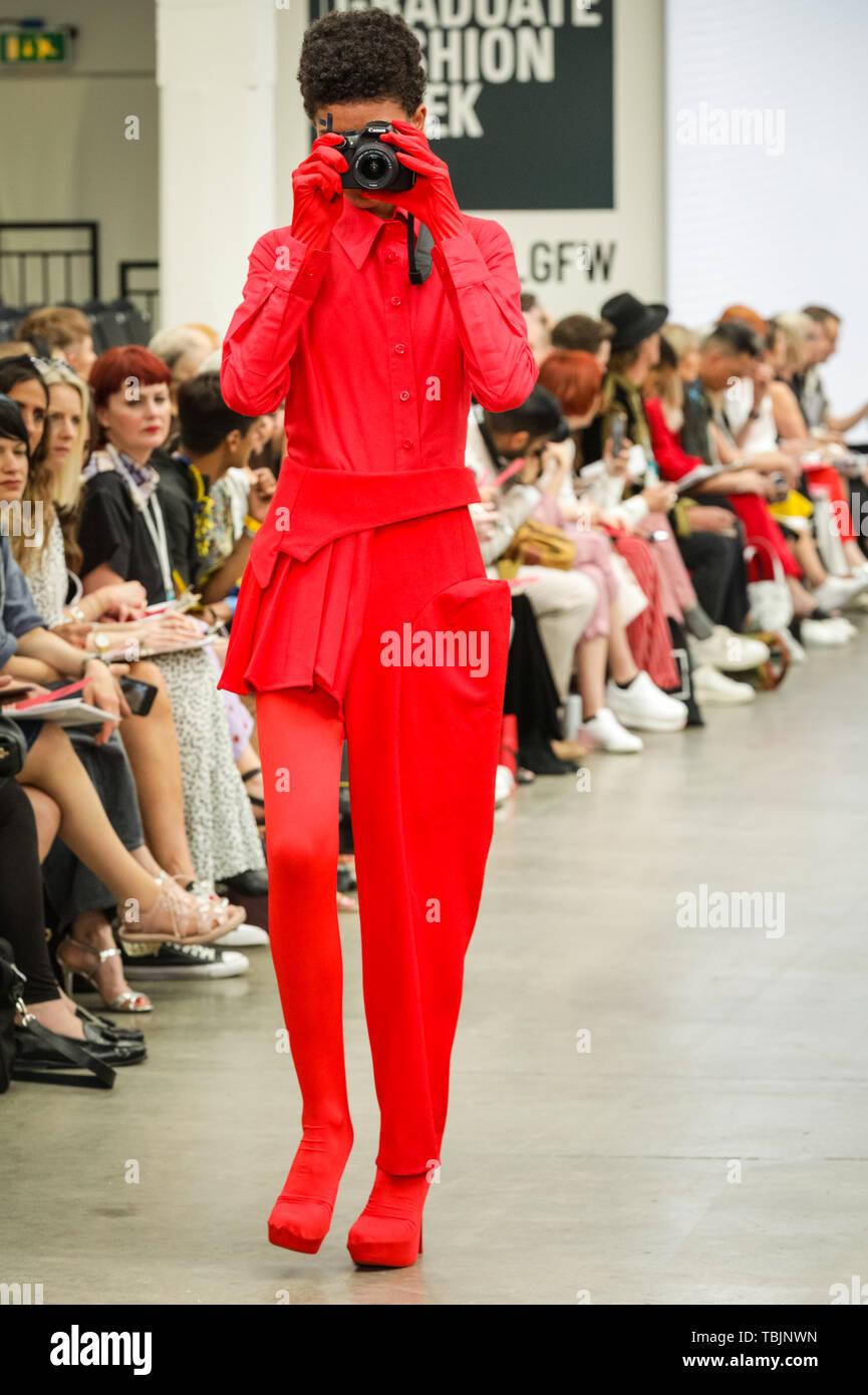 London, UK, 02 June 2019.  Liverpool John Moores University Show. A model walks the runway in  a design by  Riopelle X Ljmu Fashion, a sponsored tailoring project and collaboration of several designers. The models walk with mobile phones and cameras.  Graduate Fashion week is held at the Old Truman Brewery, and a showcase and springboard for new talent from British fashion schools to the international fashion industry. Stock Photo