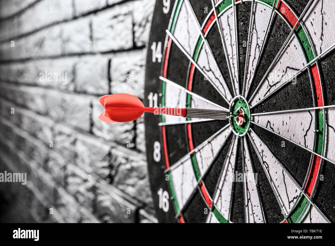 Dartboard with hit bullseye on dark brick wall, closeup Stock Photo Alamy