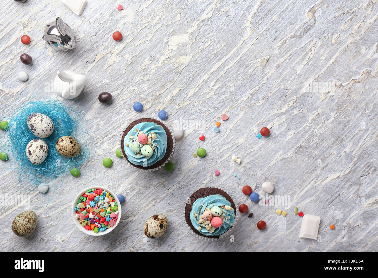 Tasty Easter cupcakes with candies on white table Stock Photo