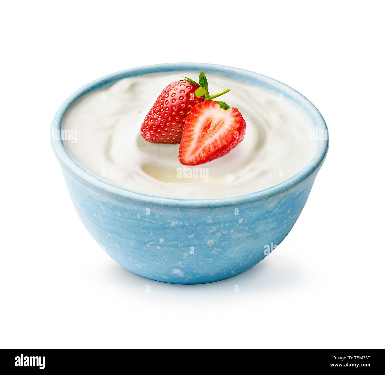 Blue bowl of yogurt with fresh beautiful strawberries isolated on white background. Half and whole strawberry light on fresh yoghurt. Stock Photo