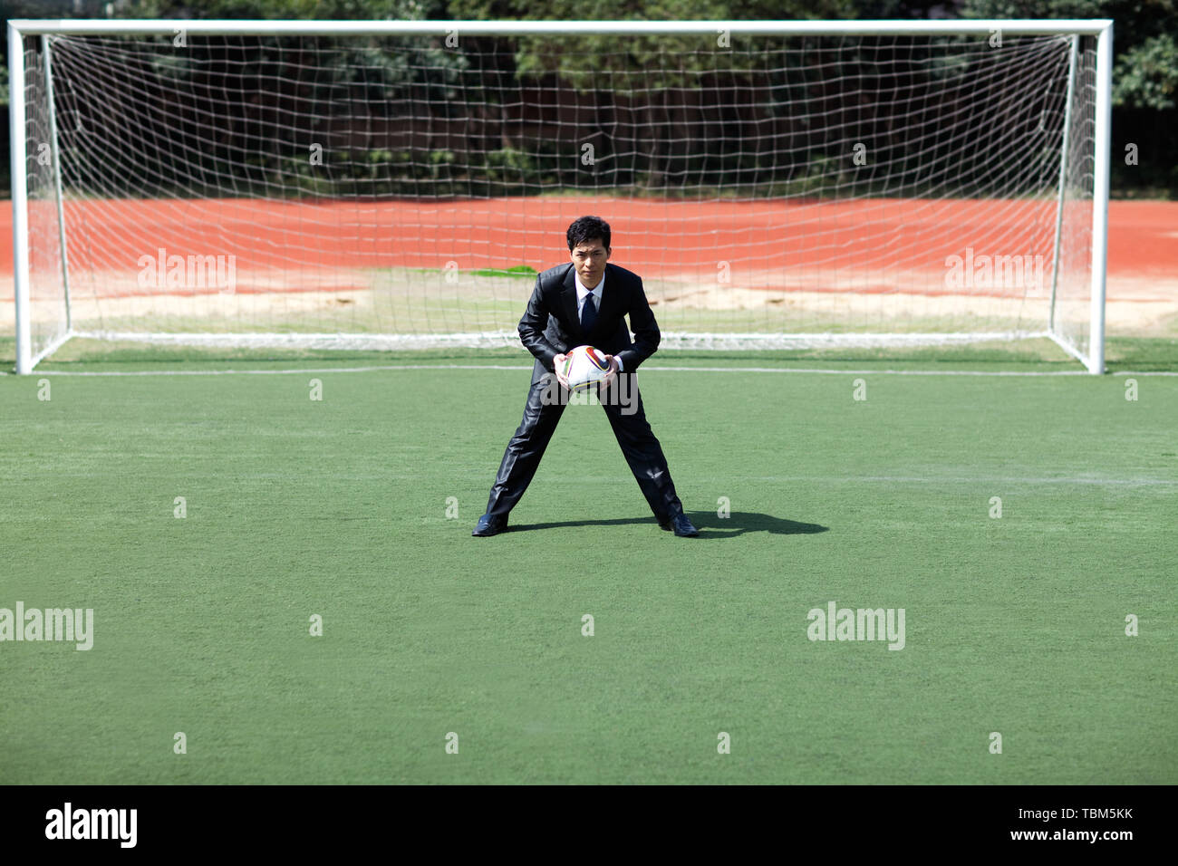 Business people playing football on a football field Stock Photo