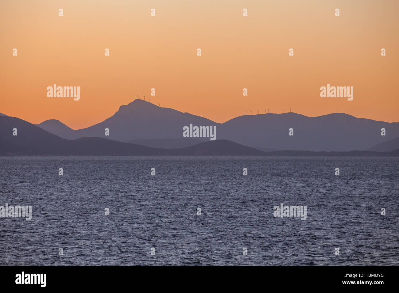 Profile of an island carpeted with wind turbines at sunset Stock Photo