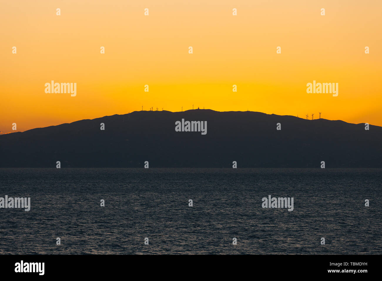 Sunset behind the profile of an island with wind turbines Stock Photo