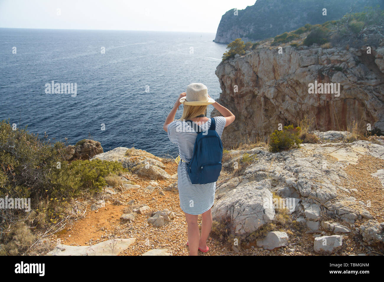 rear view of woman standing on cliff above sea Stock Photo