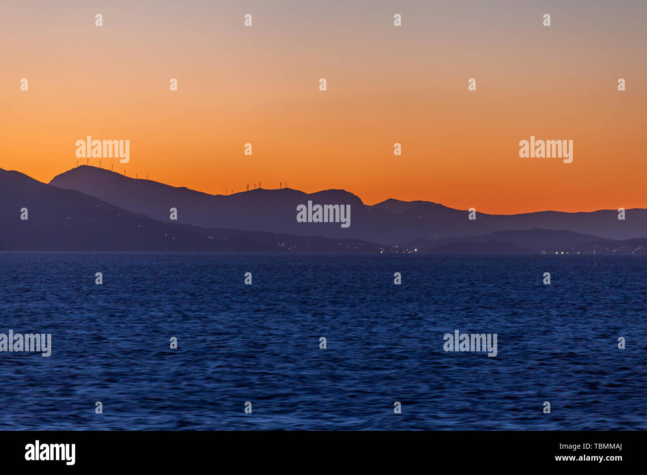 Aegean Sea islands silhouette with wind turbines at sunset Stock Photo