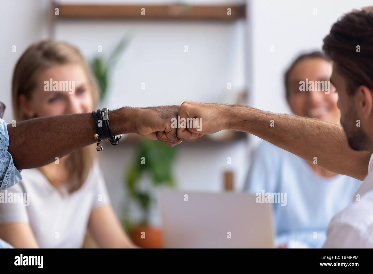 Close up diverse male hands, colleagues giving fist bump Stock Photo