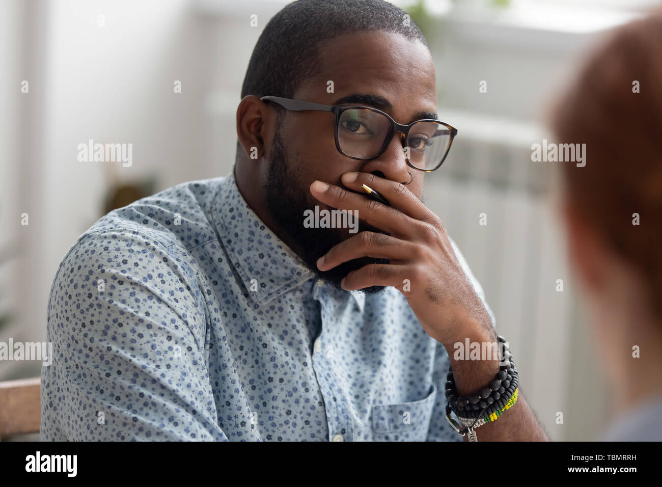 Unpleasantly surprised african-american businessman listening female caucasian coworker Stock Photo