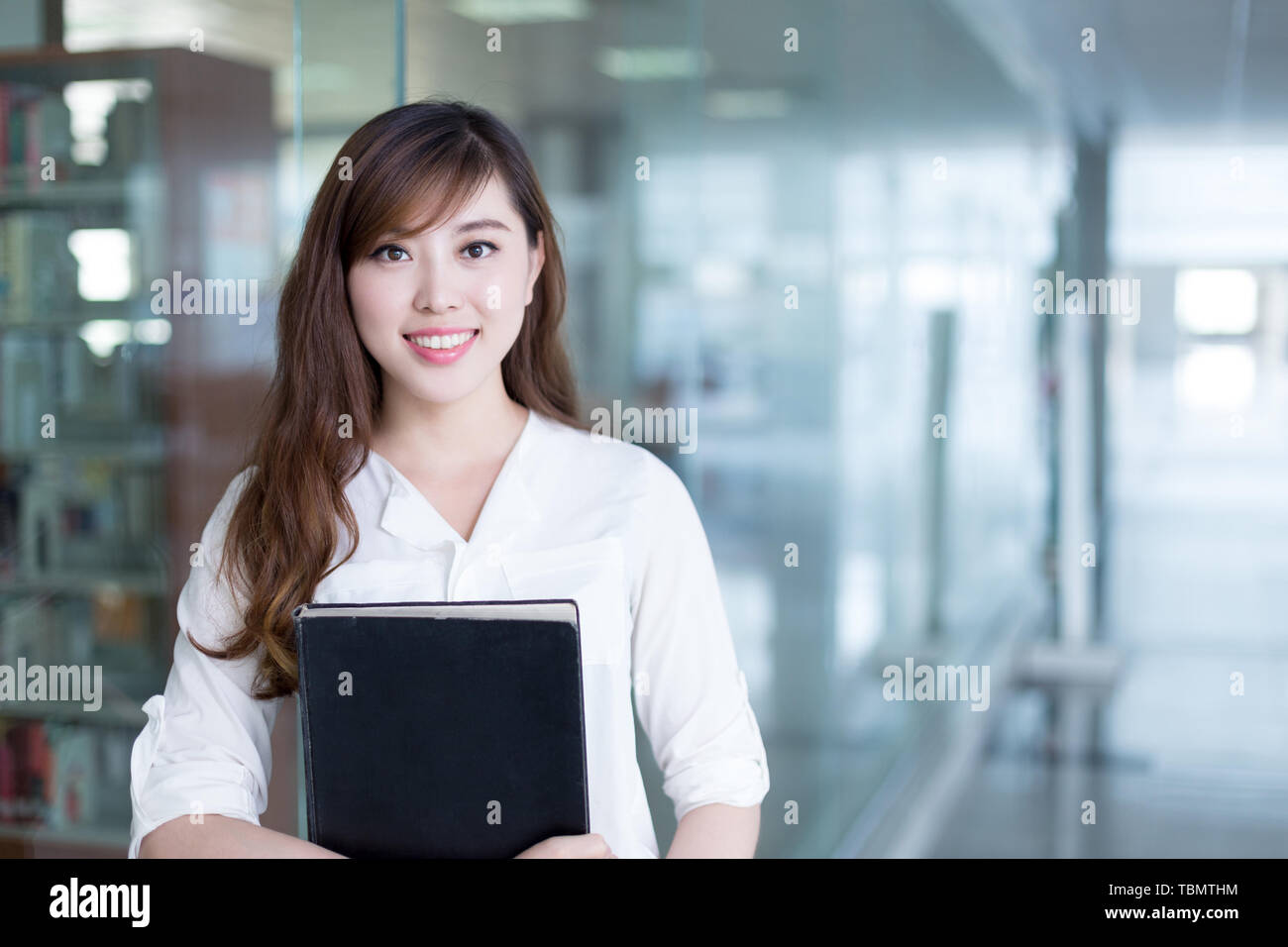 Asian beautiful female student holding book in library Stock Photo - Alamy