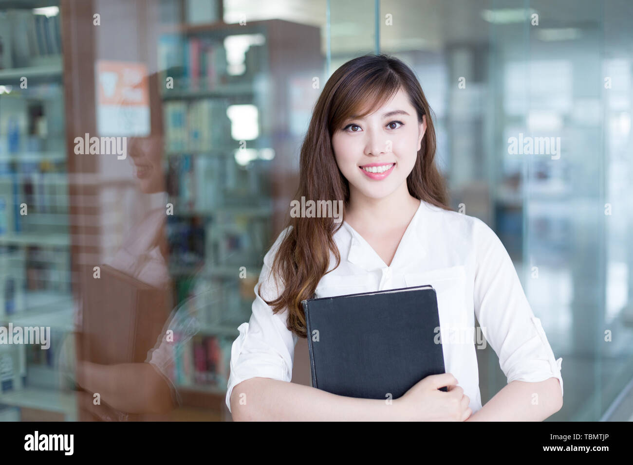 Asian beautiful female student holding book in library Stock Photo - Alamy