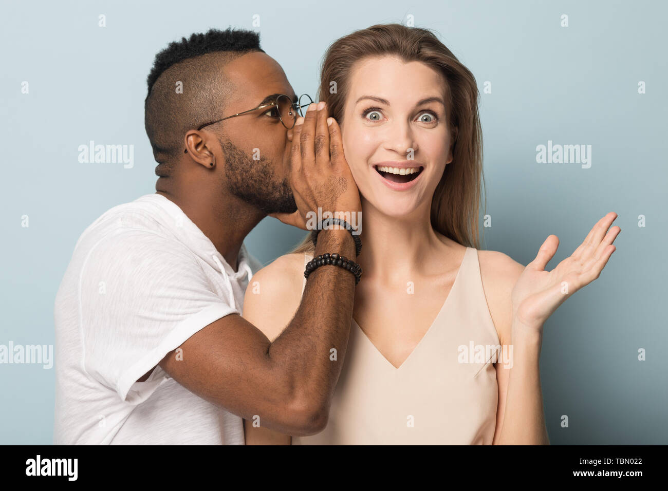 African American man tell secret to shocked caucasian female Stock Photo