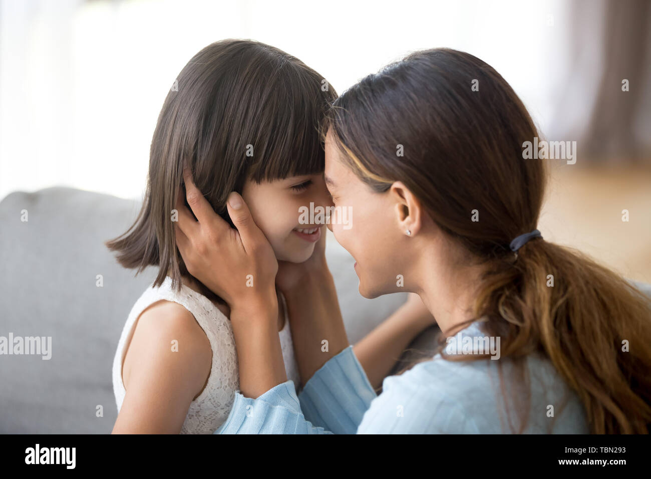 Loving mom and little daughter cuddle looking in eyes Stock Photo