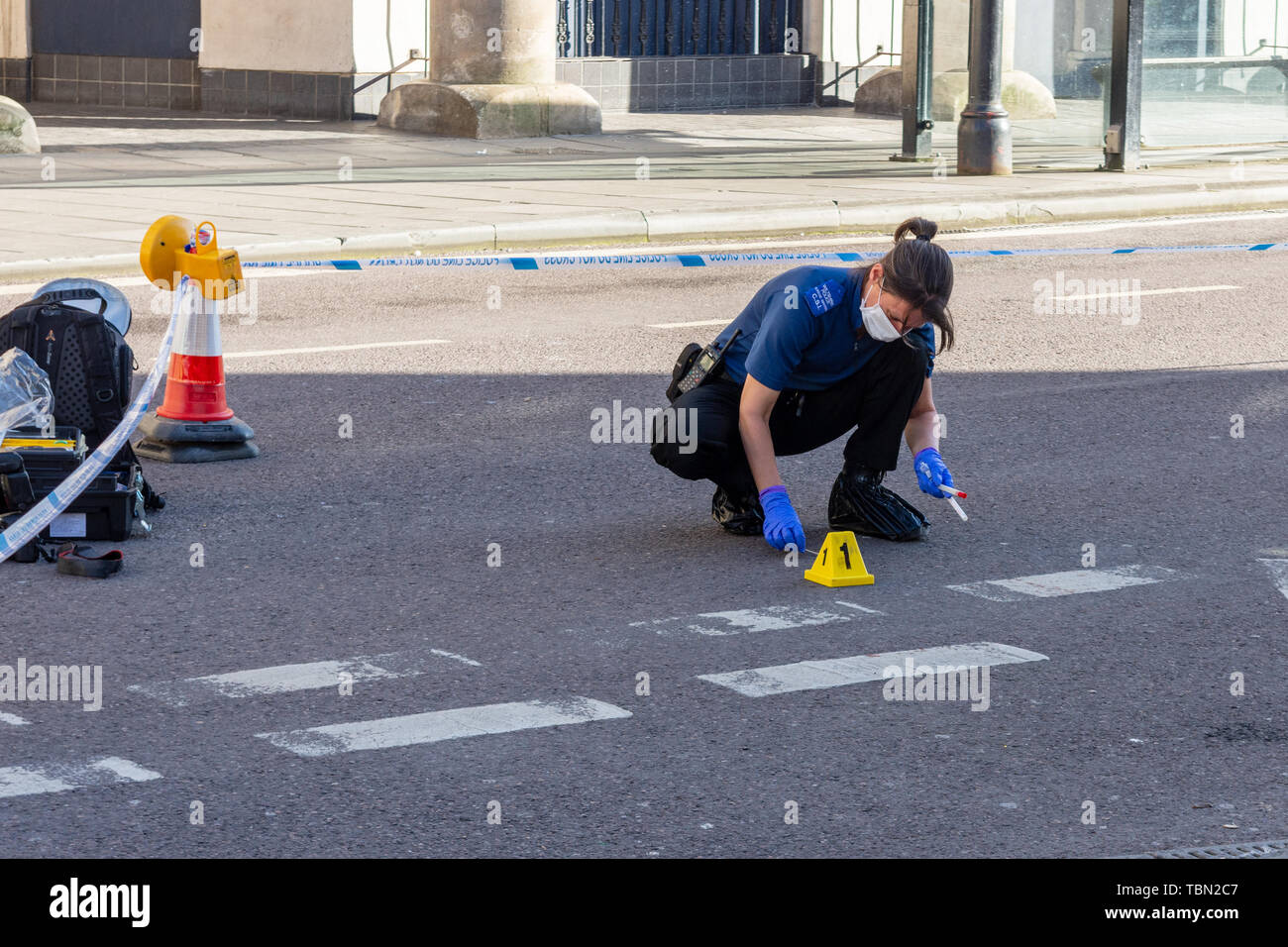 A CSI for the Wiltshire police with footcovers gloves and facemask is using swabs to collect blood evidence after an incident involving a knife Stock Photo