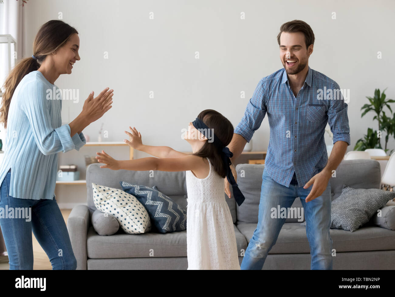 Excited parents have fun playing funny game with daughter Stock Photo