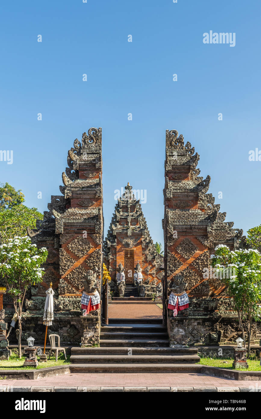 Ubud, Bali, Indonesia - February 26, 2019: Batuan Temple tower seen behind the Candi Bentar, front split gate, to the temple grounds under blue sky an Stock Photo