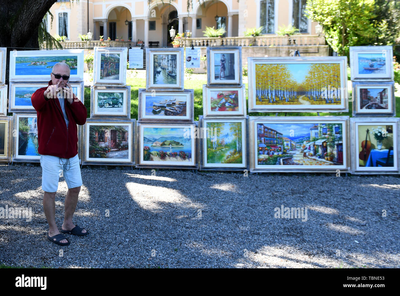 Artist man selling copies of  art works paintings in Stresa, Italy, 2019 Stock Photo