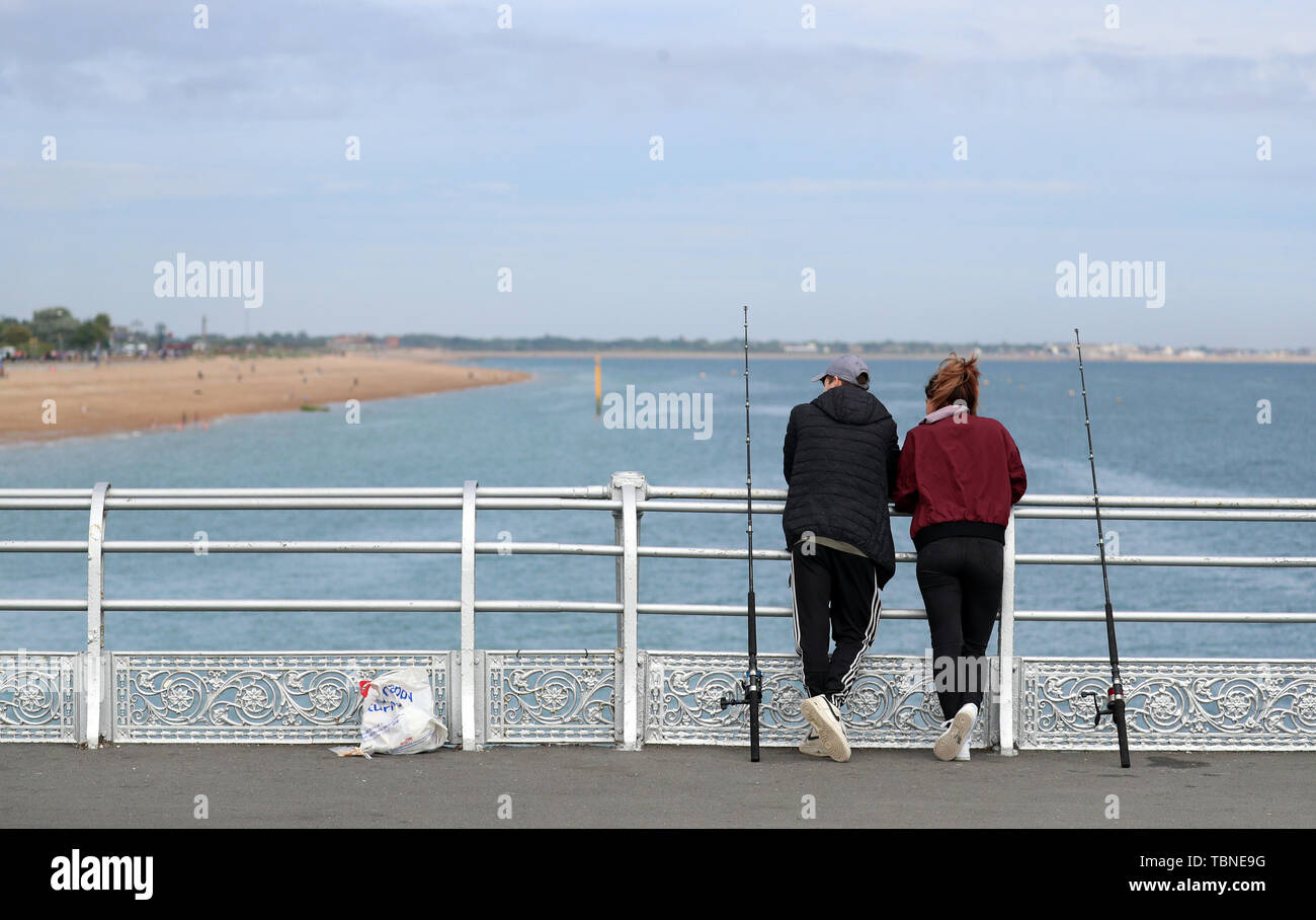 Two people look out towards the sea as they fish off of South Parade pier in Southsea, Hampshire. Stock Photo