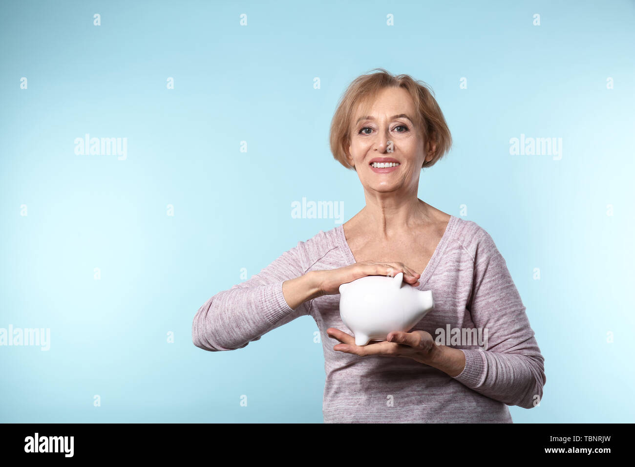 Beautiful mature woman with piggy bank on color background Stock Photo ...