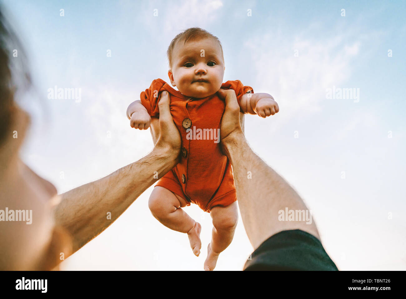 Father hands holding up infant baby outdoor Fathers day holiday happy family lifestyle dad and daughter together Stock Photo