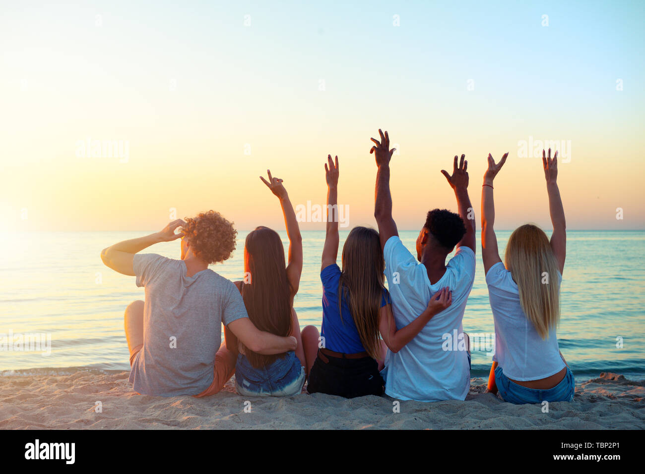Group of happy friends having fun at ocean beach at dawn Stock Photo