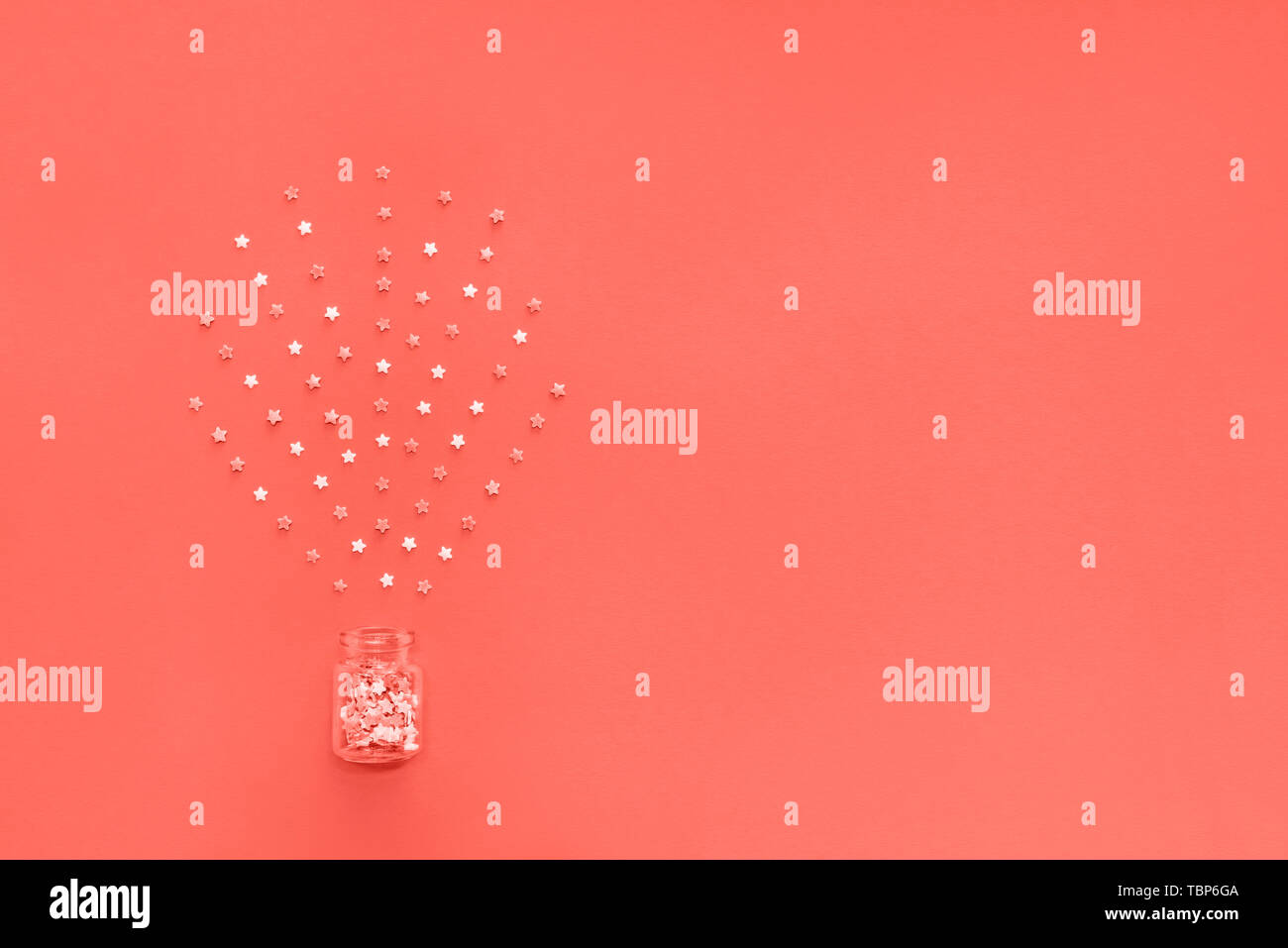 Little stars confetti on coral background. Holyday concept. Copy cpase for your text. Stock Photo