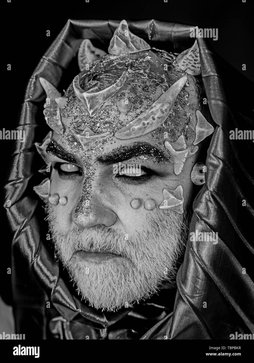Man with thorns or warts, face covered with glitters. Senior man with white beard dressed like monster. Alien, demon, sorcerer makeup. Fantasy concept Stock Photo