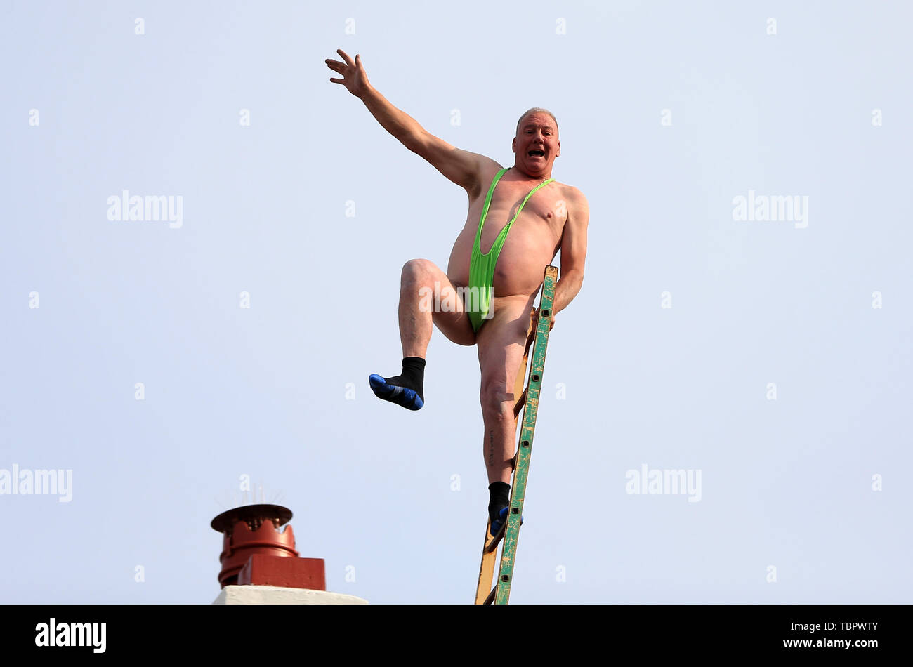2nd June 2019, Liverpool, Merseyside; Liverpool FC celebration parade after their Champions League final win over Tottenham Hotspur in Madrid on 1st June; a daring fan wearing a mankini  precariously balances on a ladder above a rooftop cheers as the team bus passes Stock Photo