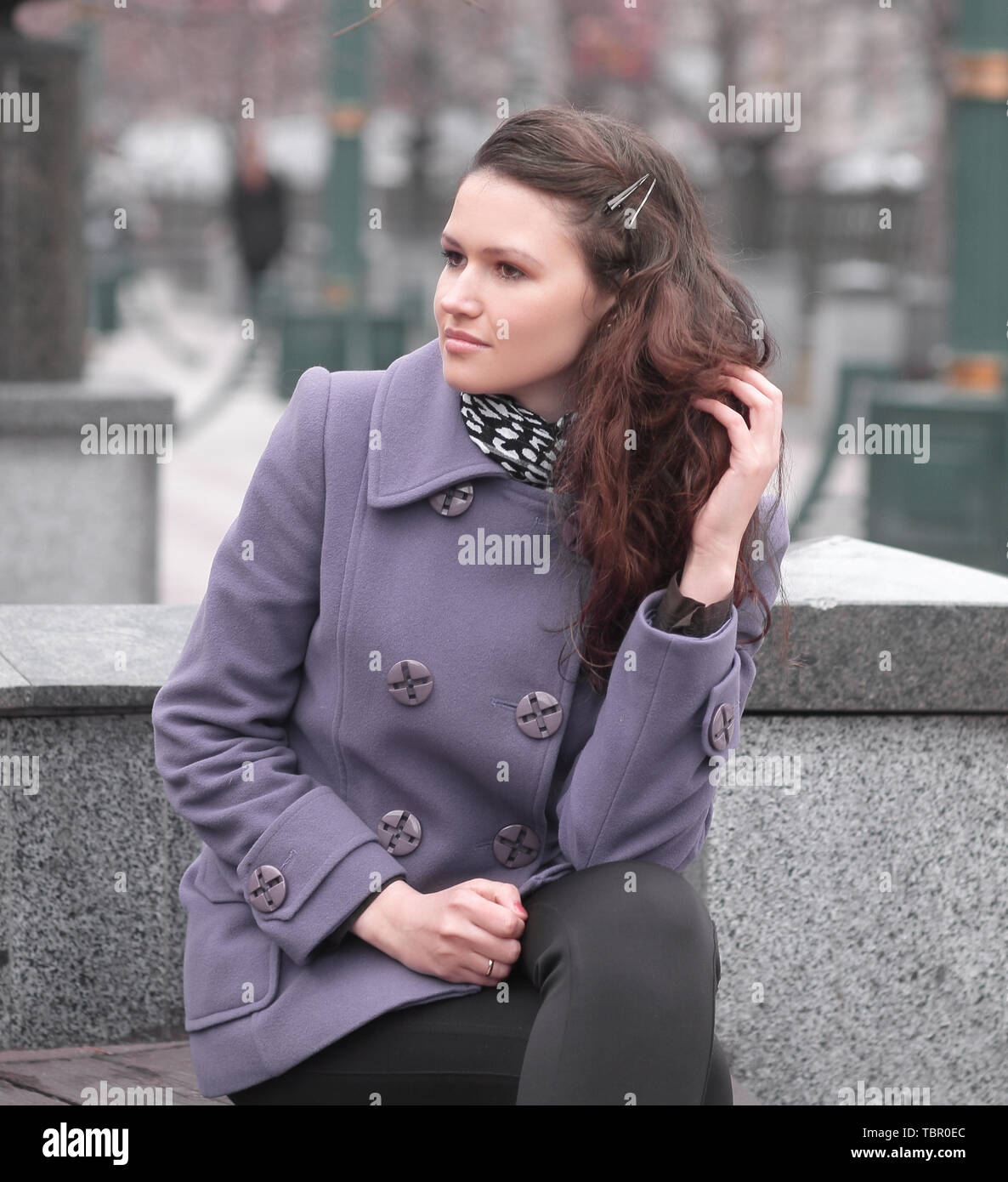 Woman In Fashionable Coat Sitting On Bench In City Stock Photo