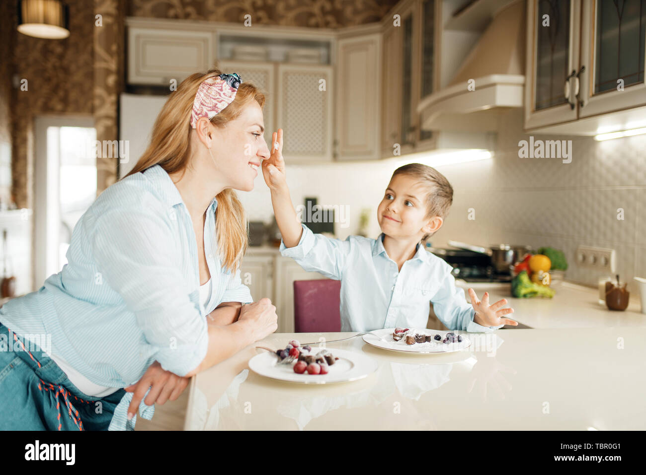 Young mother with her son tastes chocolate pastry Stock Photo